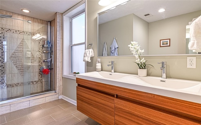 bathroom with a shower with door, vanity, and tile patterned floors