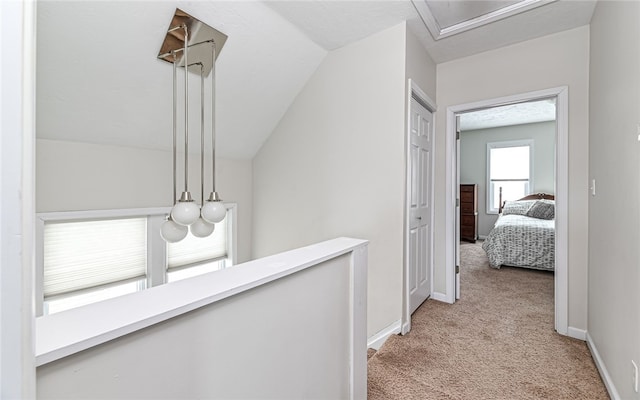 hallway featuring vaulted ceiling and light carpet