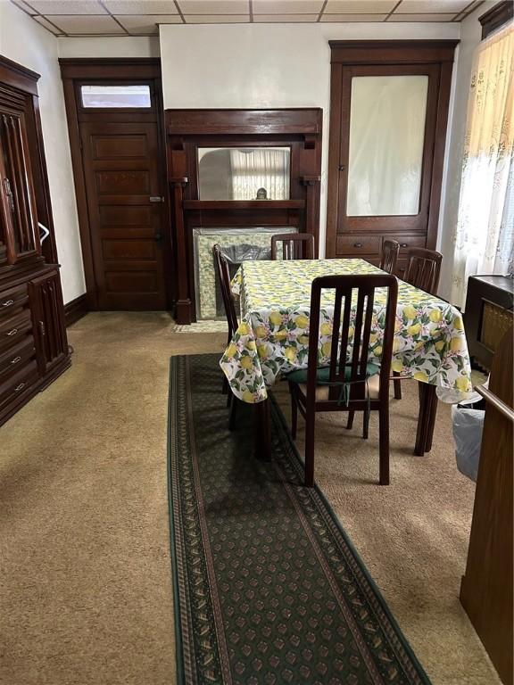 carpeted dining area with a paneled ceiling