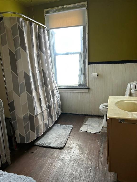 bathroom featuring vanity, hardwood / wood-style flooring, wooden walls, and toilet