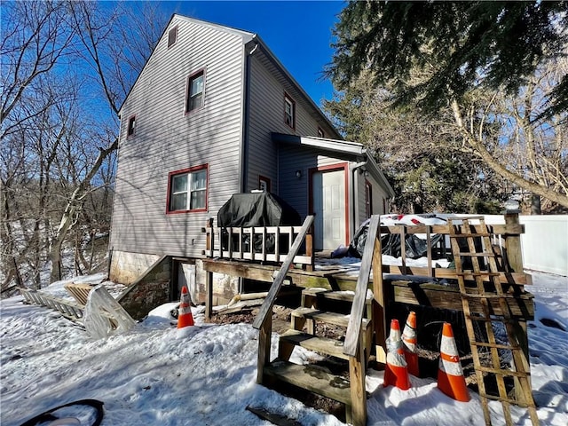 snow covered house with a wooden deck