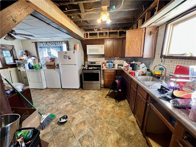 kitchen featuring sink, white appliances, ceiling fan, washer and clothes dryer, and decorative backsplash