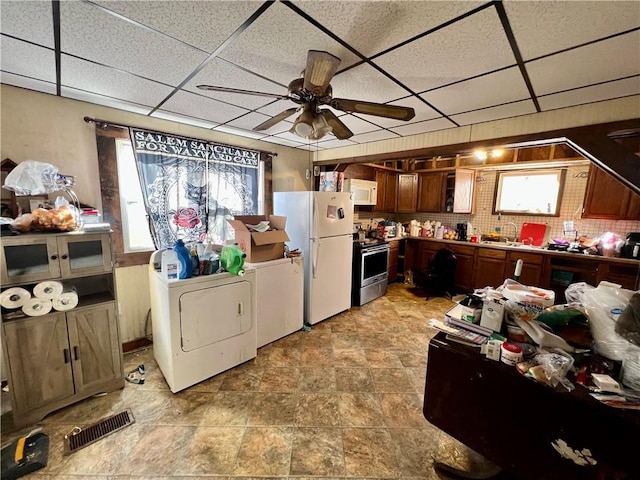 kitchen featuring washing machine and dryer, a paneled ceiling, white appliances, and decorative backsplash