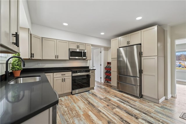 kitchen with appliances with stainless steel finishes, sink, and light hardwood / wood-style floors