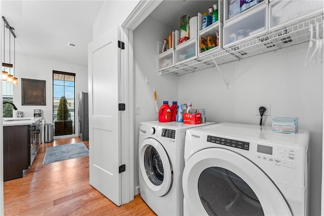 laundry room featuring washing machine and dryer and light hardwood / wood-style flooring