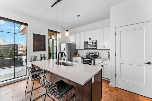 kitchen featuring white cabinetry, a kitchen bar, stainless steel appliances, and a center island with sink