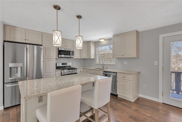 kitchen featuring appliances with stainless steel finishes, a kitchen island, a breakfast bar, and light stone countertops