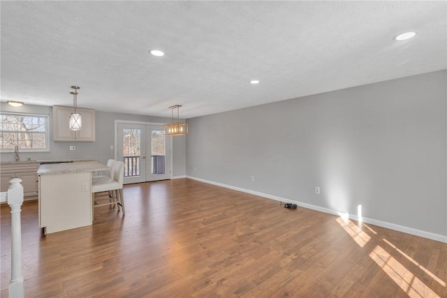 unfurnished living room featuring french doors, dark wood-type flooring, sink, and a textured ceiling