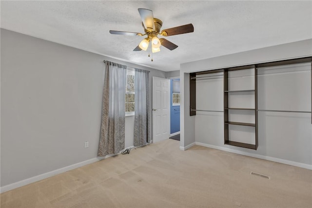 unfurnished bedroom with light carpet, a textured ceiling, ceiling fan, and a closet