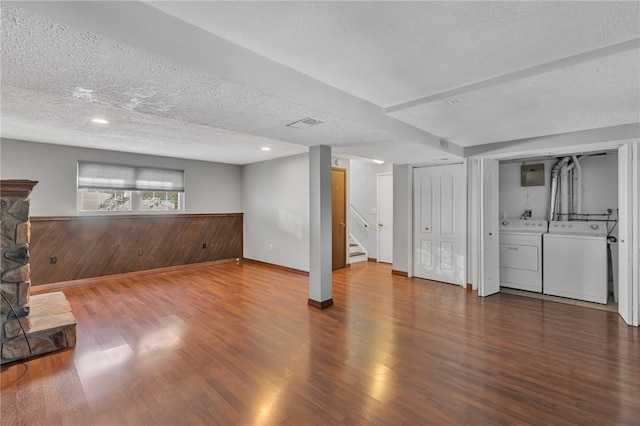 basement with separate washer and dryer, hardwood / wood-style floors, a textured ceiling, and wood walls