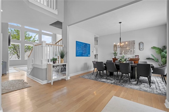 dining room featuring a towering ceiling, a chandelier, and hardwood / wood-style floors