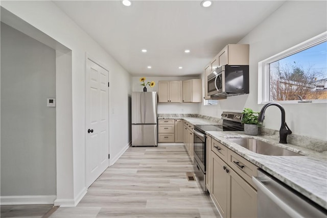 kitchen with sink, light wood-type flooring, stainless steel appliances, and light stone countertops