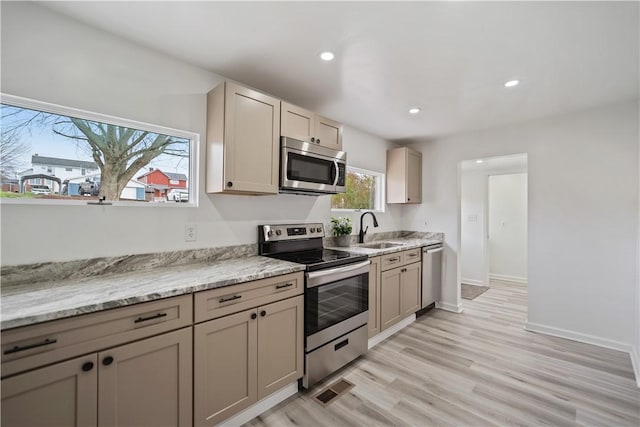 kitchen with light stone counters, stainless steel appliances, sink, and plenty of natural light