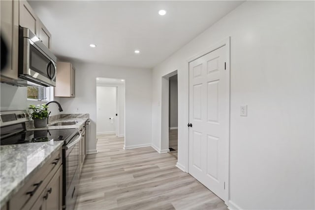 kitchen featuring sink, stainless steel appliances, light hardwood / wood-style floors, and light stone countertops