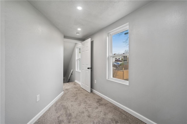 hallway featuring light colored carpet and a textured ceiling