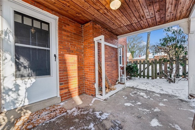 snow covered property entrance featuring a patio area