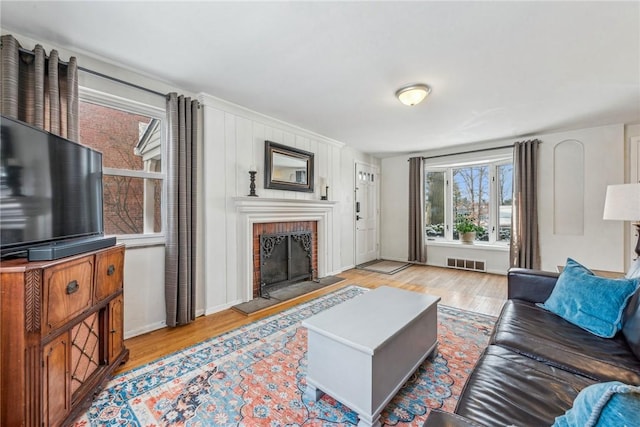 living room with a brick fireplace and light hardwood / wood-style flooring