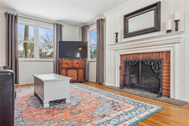 living room featuring wood-type flooring, crown molding, and a fireplace