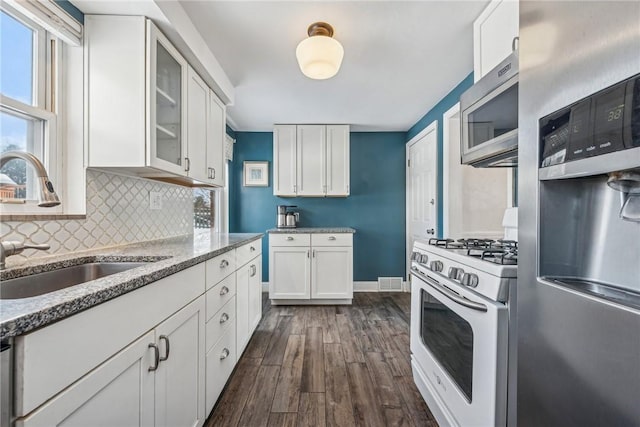 kitchen with sink, light stone counters, white cabinets, stainless steel appliances, and backsplash