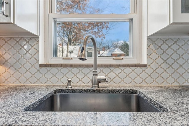 kitchen with sink, light stone counters, and decorative backsplash