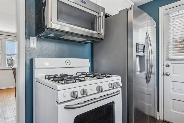 kitchen featuring hardwood / wood-style flooring, white gas stove, and white cabinets