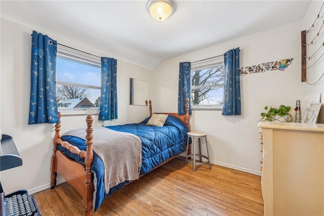 bedroom featuring multiple windows, vaulted ceiling, and hardwood / wood-style flooring