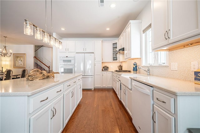 kitchen featuring dark hardwood / wood-style flooring, white cabinets, pendant lighting, white appliances, and backsplash