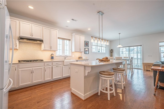 kitchen featuring white cabinetry, pendant lighting, a center island, and white refrigerator