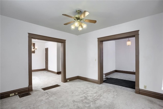 empty room featuring light carpet and ceiling fan with notable chandelier