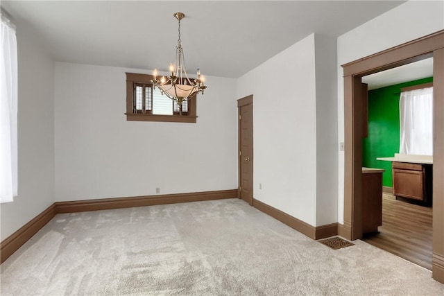 empty room featuring carpet floors and a notable chandelier