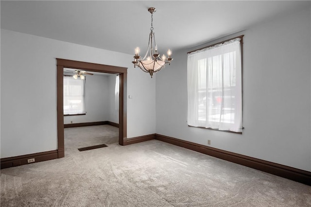 spare room featuring an inviting chandelier, a wealth of natural light, and carpet flooring