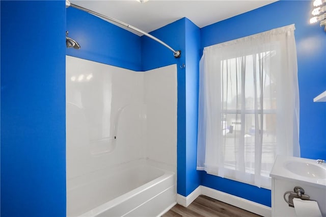 bathroom with hardwood / wood-style flooring, sink, and washtub / shower combination