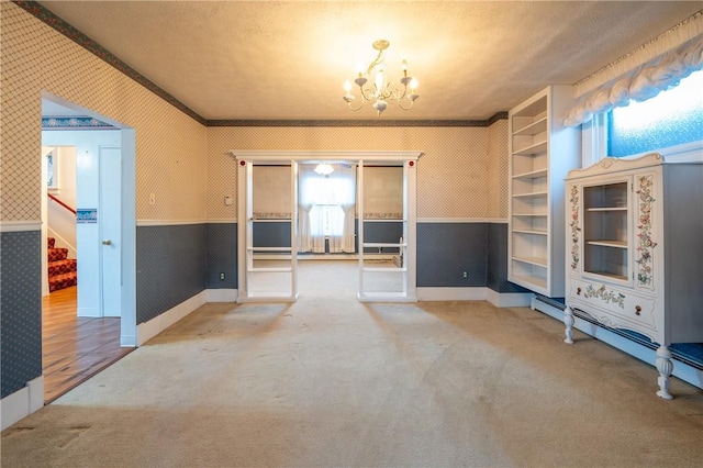 unfurnished living room featuring ornamental molding, a baseboard heating unit, a textured ceiling, and a chandelier