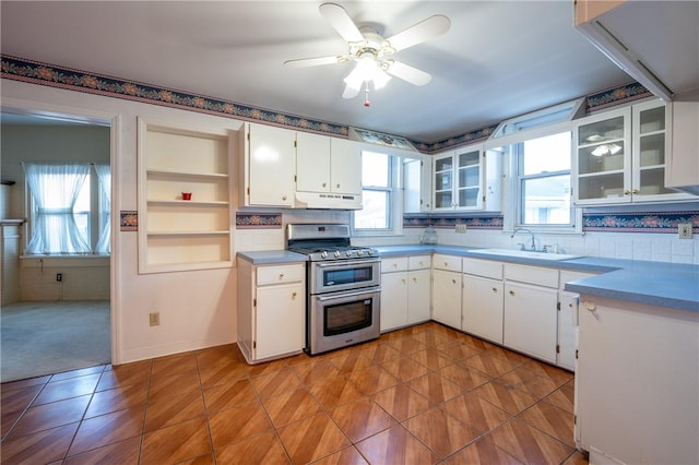 kitchen featuring white cabinetry, a healthy amount of sunlight, sink, and range with two ovens