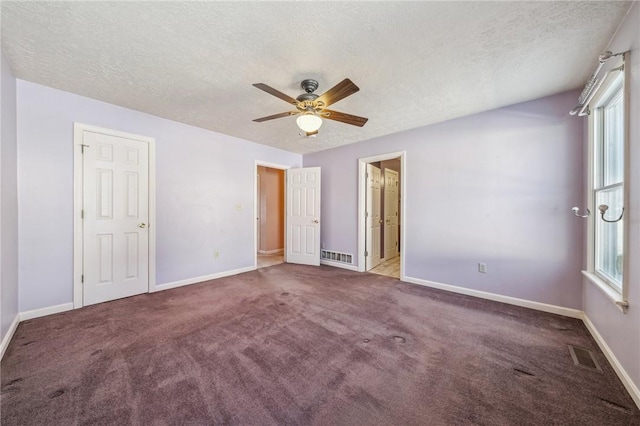 unfurnished bedroom featuring multiple windows, ceiling fan, carpet, and a textured ceiling