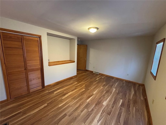 unfurnished bedroom with dark wood-type flooring and a closet