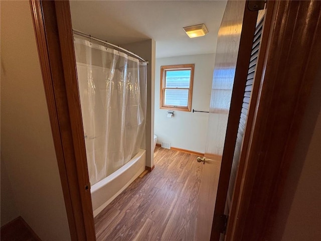 bathroom with shower / tub combo, wood-type flooring, and toilet