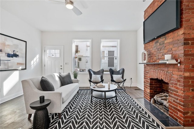 living room with a brick fireplace, dark hardwood / wood-style floors, and ceiling fan