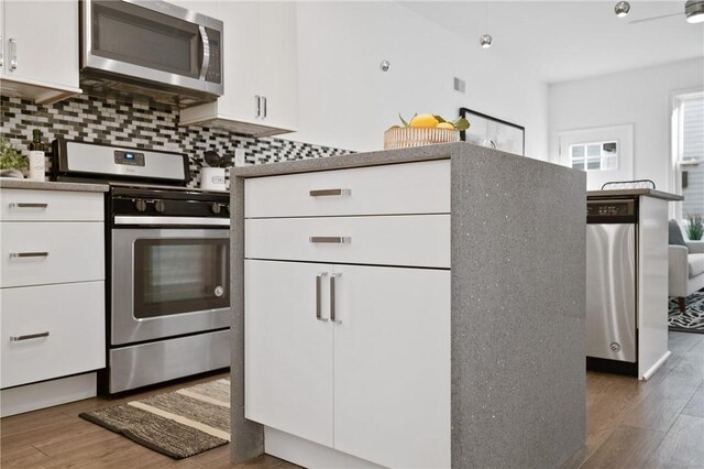 kitchen featuring white cabinetry, backsplash, dark hardwood / wood-style flooring, and appliances with stainless steel finishes