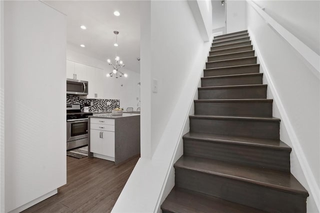 stairs featuring hardwood / wood-style flooring and a notable chandelier