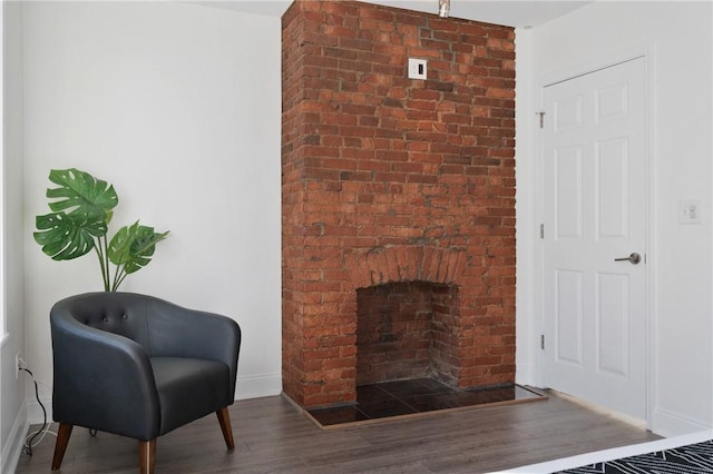 living area with a brick fireplace and dark wood-type flooring