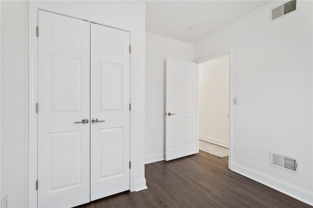 unfurnished bedroom with dark wood-type flooring and a closet