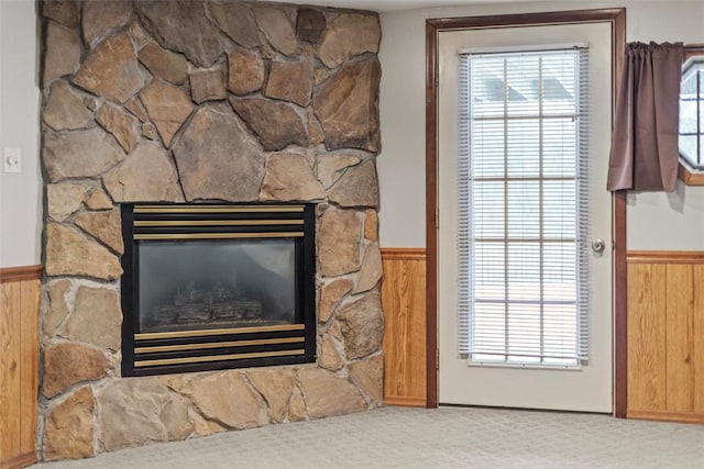 room details with a stone fireplace, carpet floors, and wooden walls