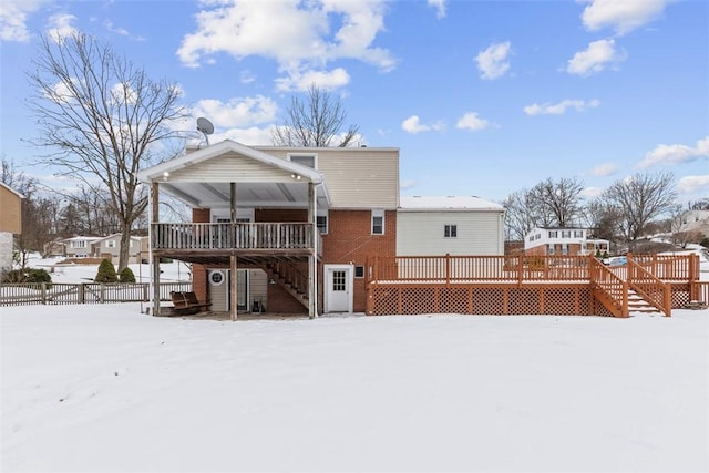 snow covered back of property with a deck