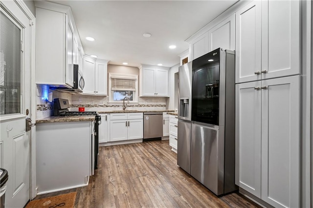 kitchen with sink, white cabinets, backsplash, stainless steel appliances, and dark wood-type flooring