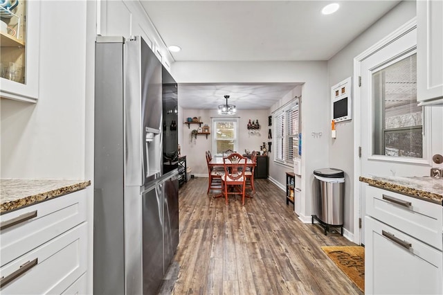 kitchen with white cabinetry, light stone countertops, dark wood-type flooring, and stainless steel fridge