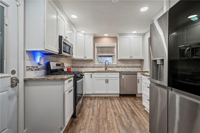 kitchen with stainless steel appliances, sink, white cabinets, and dark hardwood / wood-style floors