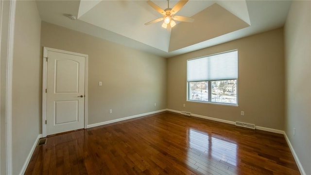 spare room featuring ceiling fan, dark hardwood / wood-style flooring, and a tray ceiling