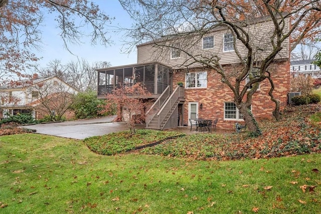 rear view of house with a patio, a yard, and a sunroom