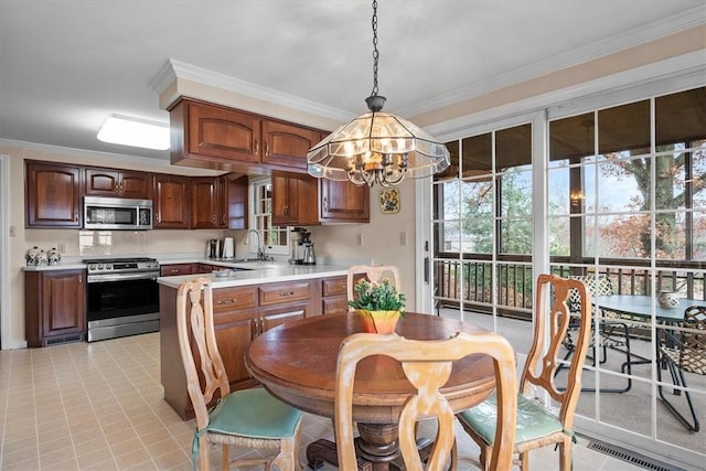 kitchen featuring pendant lighting, light tile patterned floors, crown molding, and appliances with stainless steel finishes